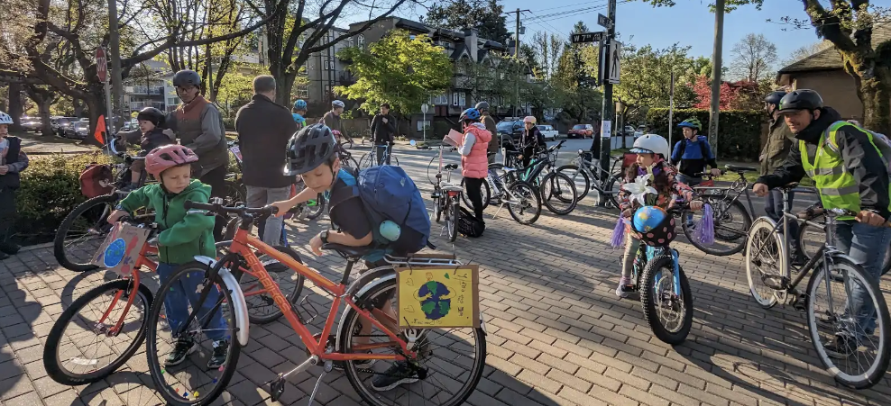 Several students and parents stop with their bikes in a school courtyard.