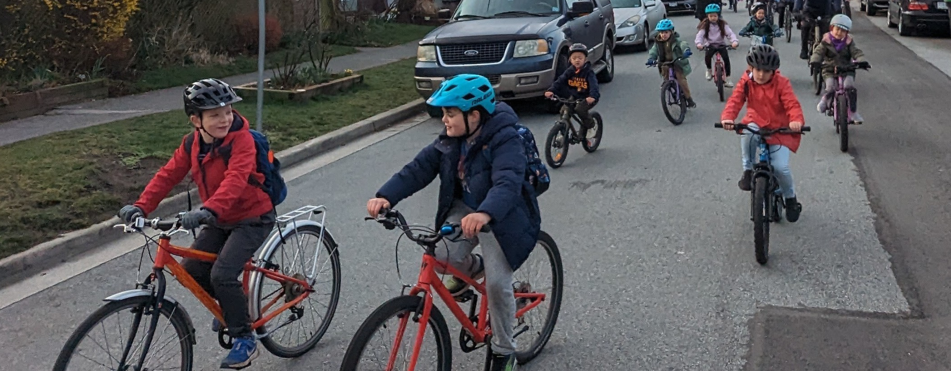 Two boys have a conversation at the front of the group while riding in a bike bus on a residential street.