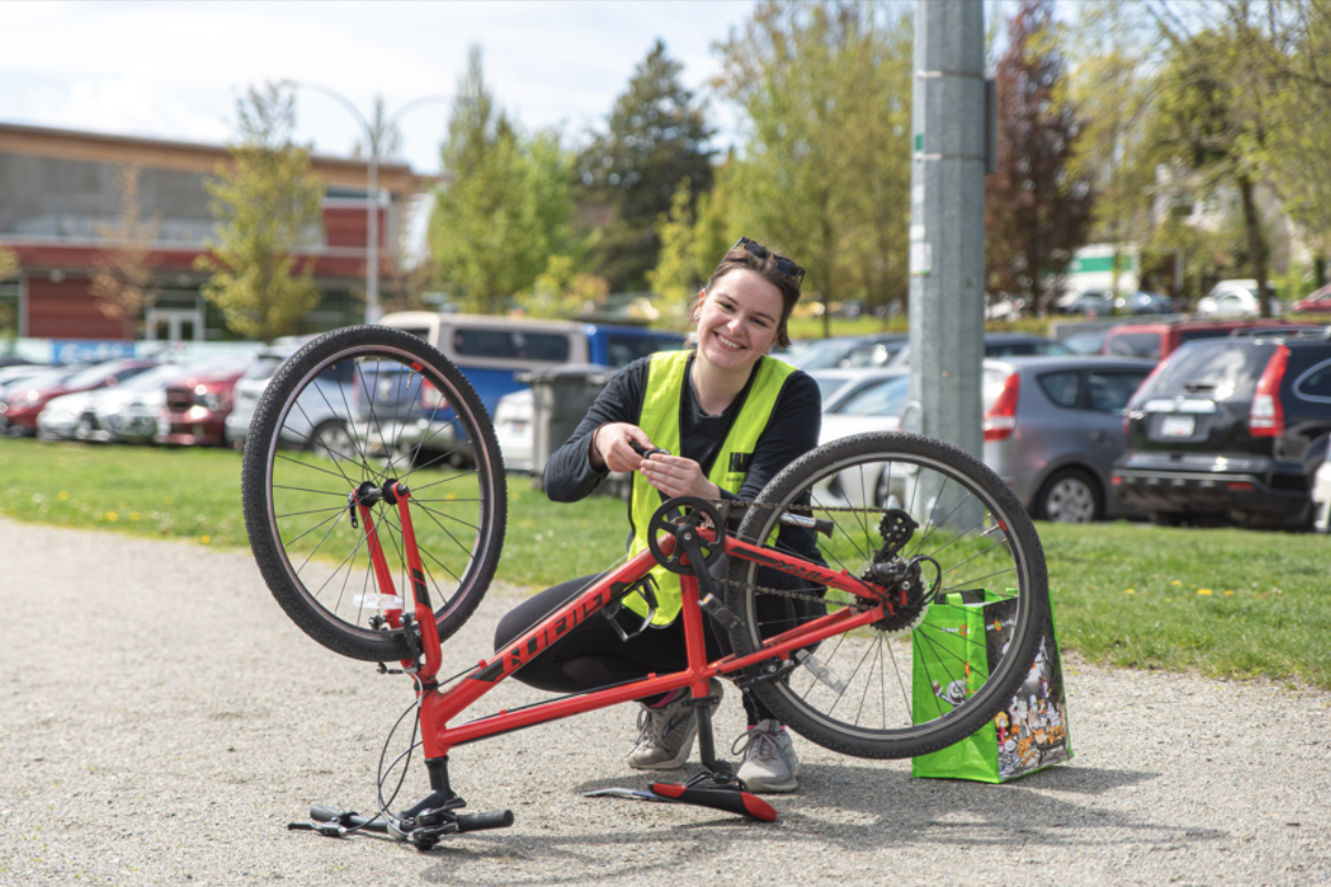 An instructor kneels and does bike maintenance on a bike that is flipped over.