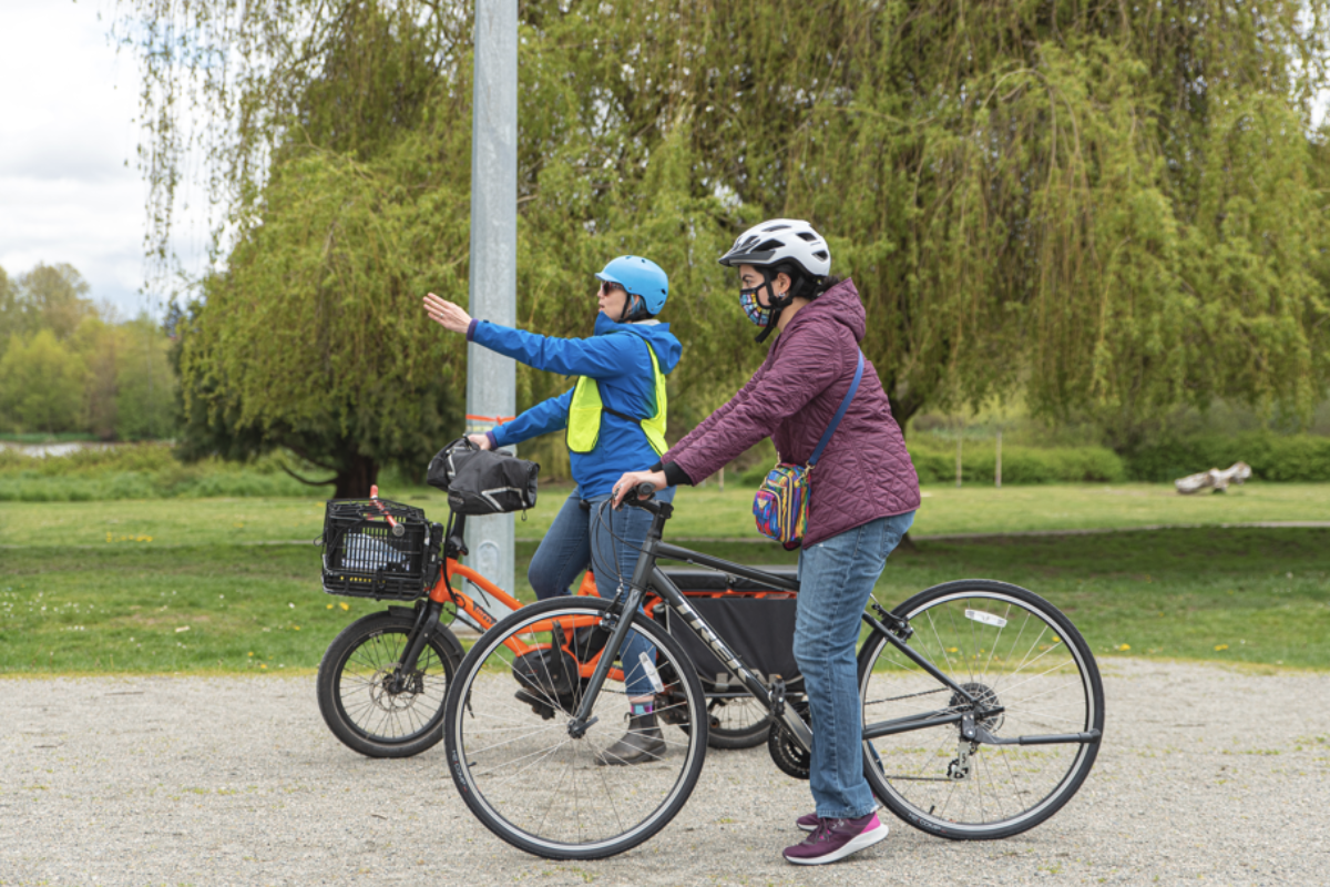 An instructor shows a participant something in the distance. They are both on bikes.