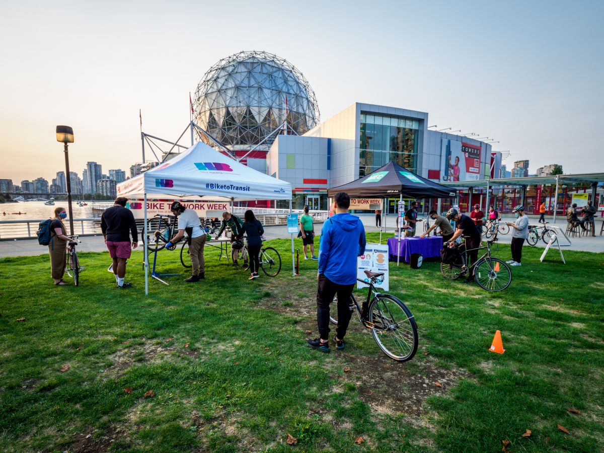 Several people wait in line to have their bikes repaired at the Science World Knowledge HUB station as part of Bike to Work Week