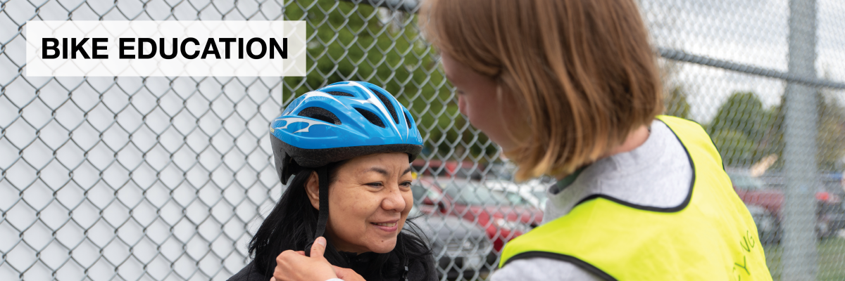 Bike Education. A bike education instructor helps an adult woman adjust her bike helmet