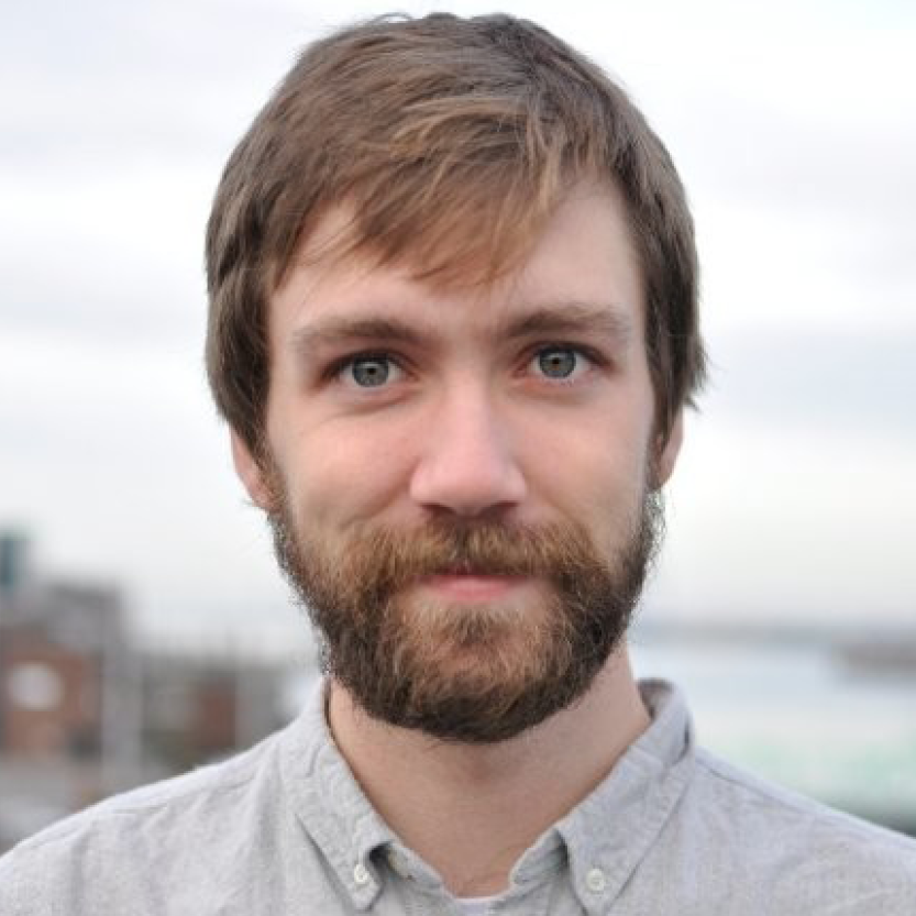 A portrait picture of Cody Gerow. He is a white man in his mid to late-20s. He has light brown hair, a moustache and short beard.