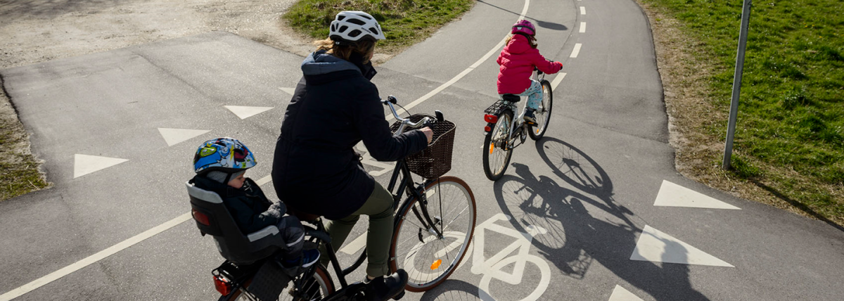 An photo of a mother and her two children cycling along a cycle highway in Denmark.