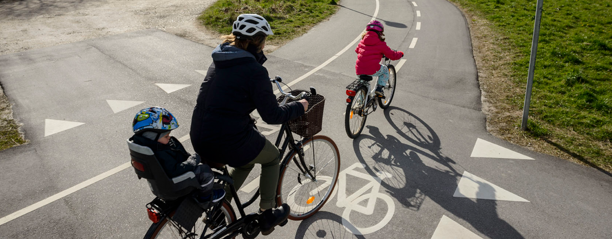 A woman is riding with her two young children on a cycle highway in Europe.