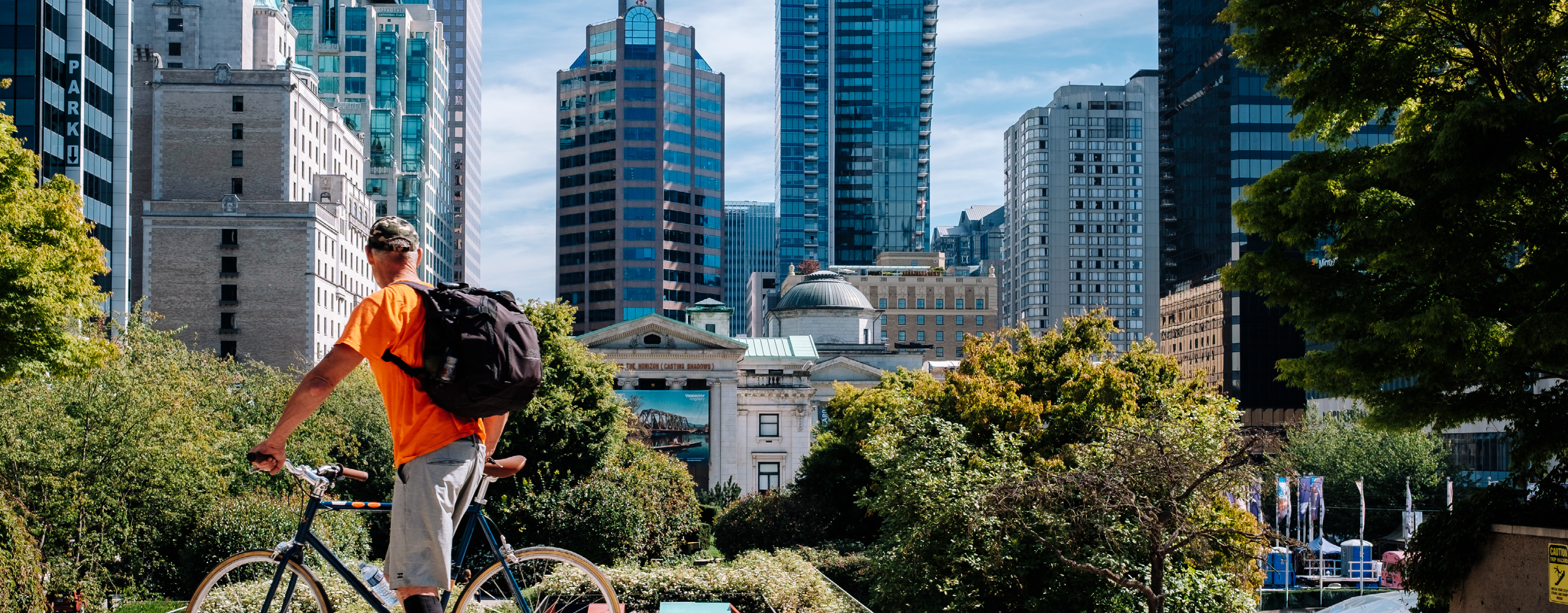 An person cycling stops to look at Vancouver's building landscape.