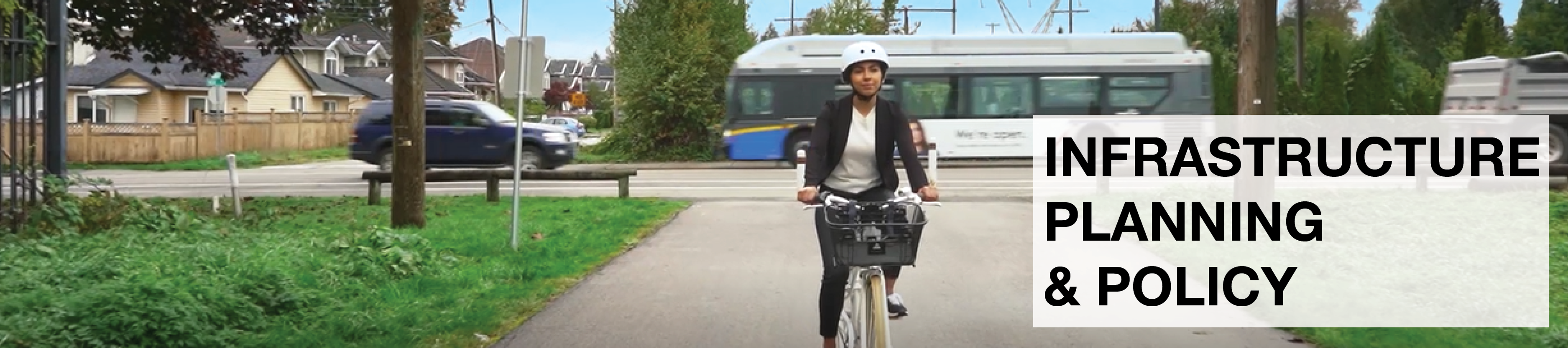Infrastructure Planning & Policy. A woman rides her bike along a multi-use path in Surrey. Behind her we see a vehicle and a bus drive by on the road.