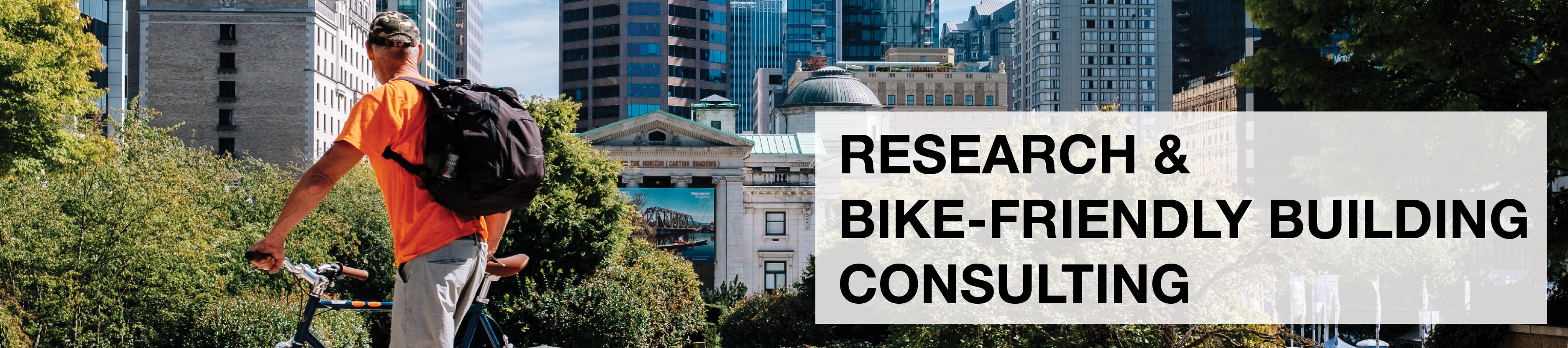 Research & Bike-Friendly Building Consulting. A man stands with his bike and looks at downtown Vancouver's building landscape.
