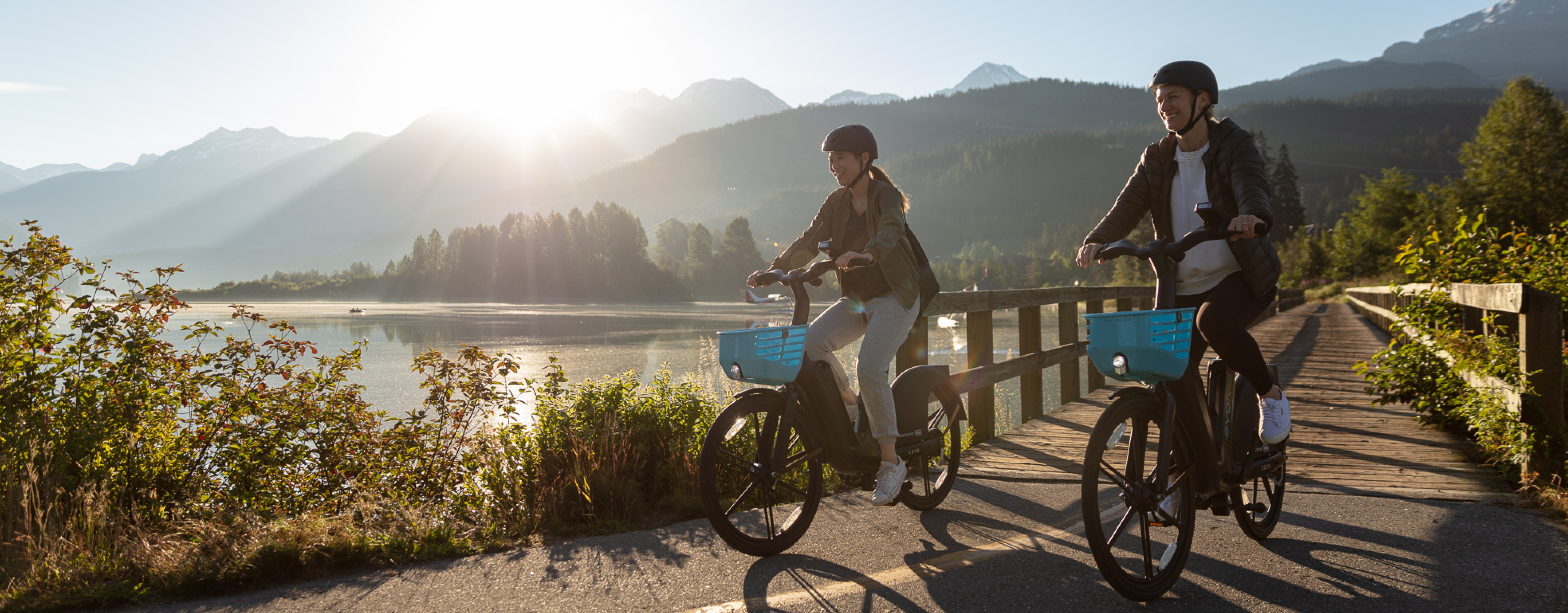 Two women ride Evolve e-bikes on a trail in Whistler.