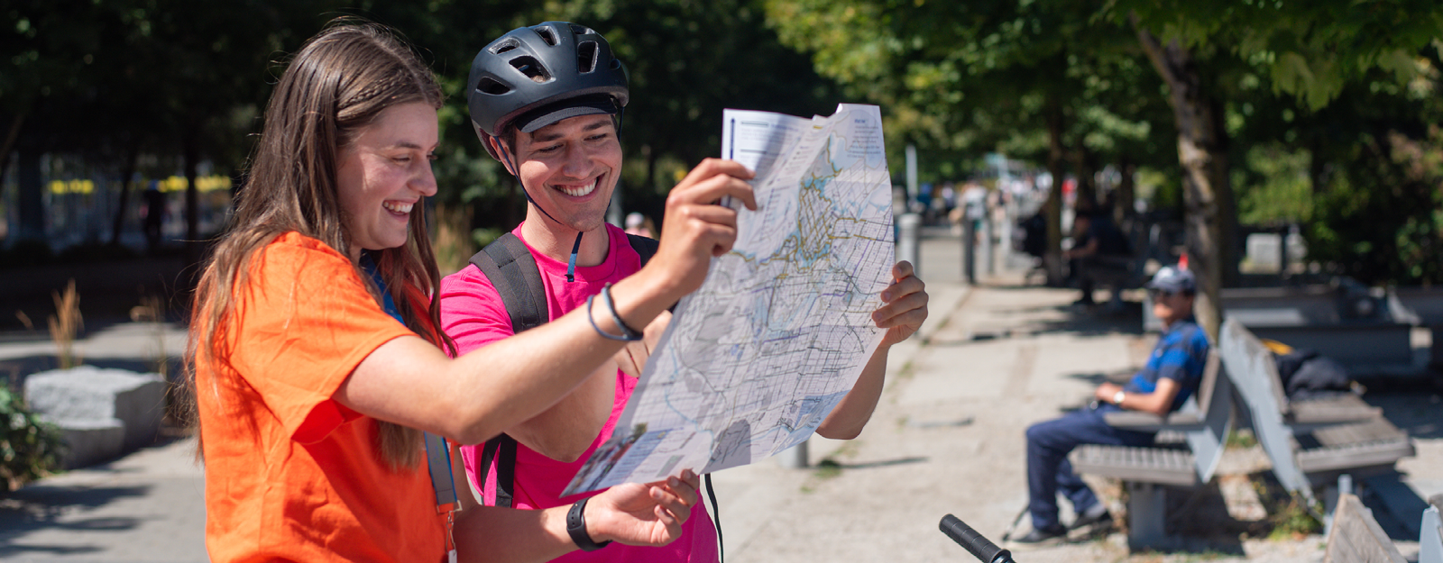 A young man and woman smile and look at a bike map together.