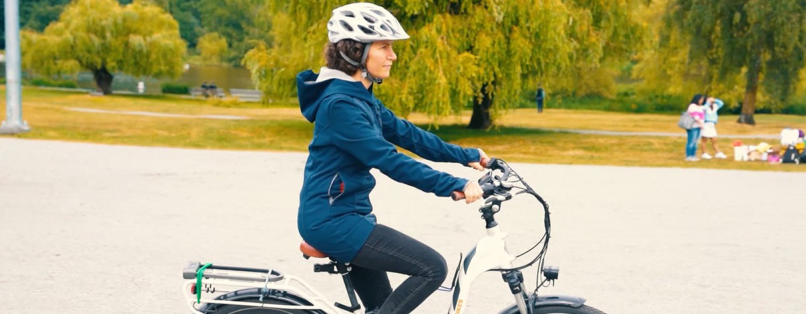 A white woman in her 40s rides an e-bike on a gravel field at Trout Lake.