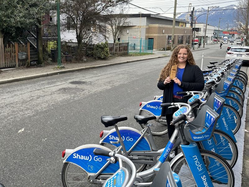 Mia Kohout, general manager at Mobi by Shaw Go, stand beside a Mobi Bike Share station with her HUB Bike Award