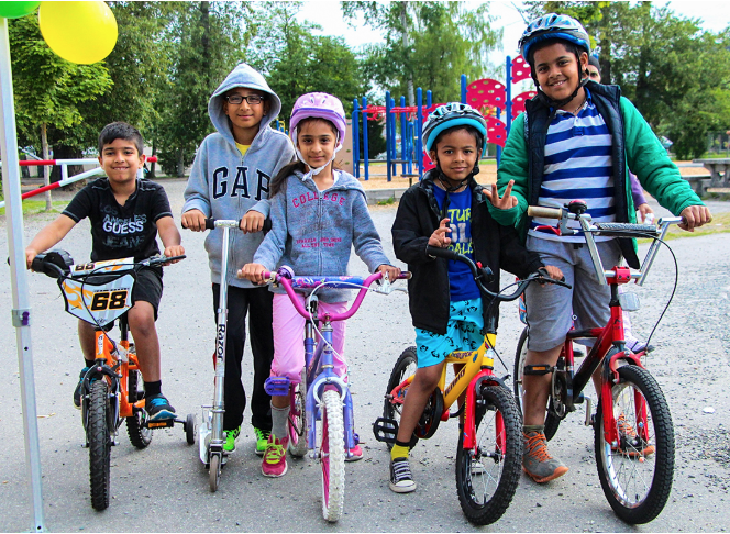 A group of 5 smiling students on bikes.