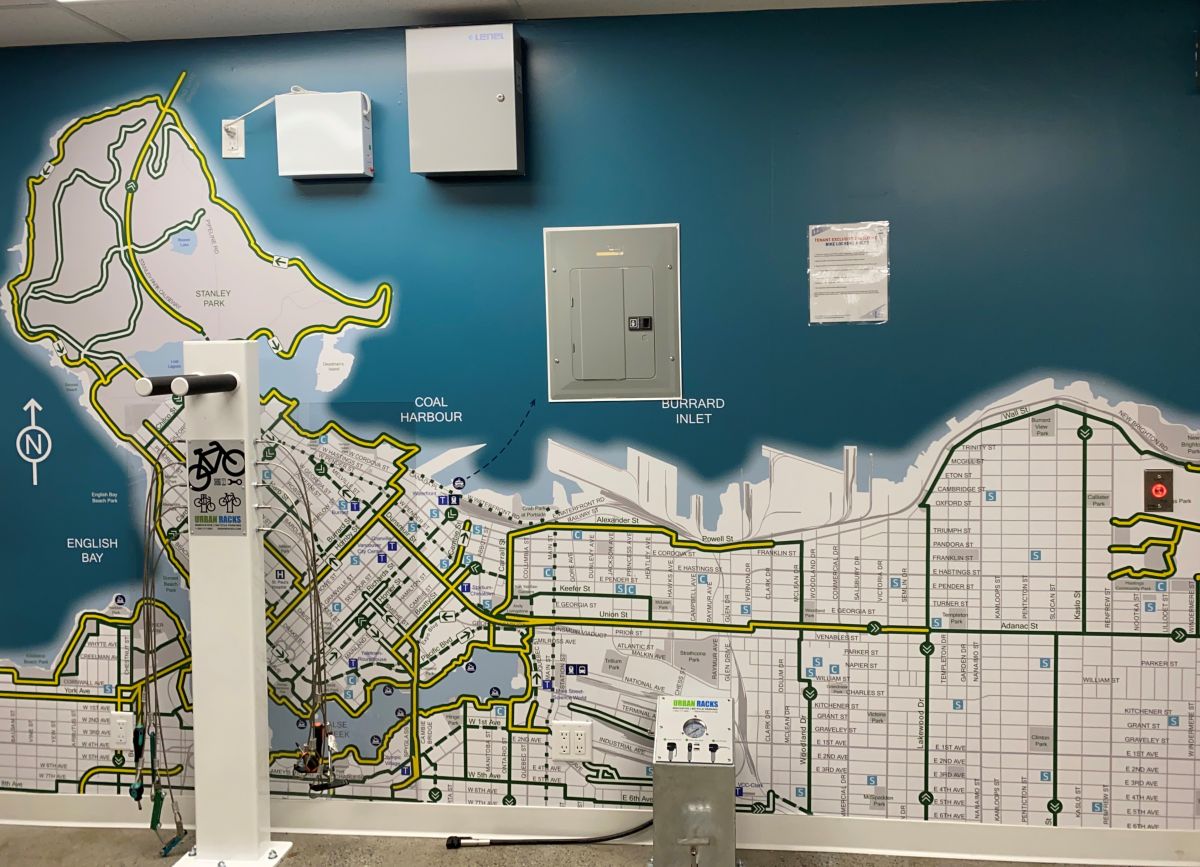 The new bike repair station inside the Bentall Centre. The station includes a bike stand and air pump. On the wall behind the station, there is a map painted on the wall outlining all of the bike routes in Vancouver.