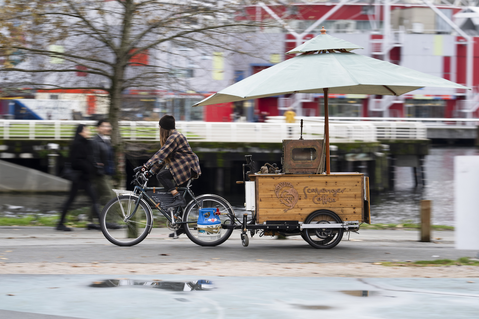 A photo of Diana biking with the Scavenger Coffee cart towing behind her.