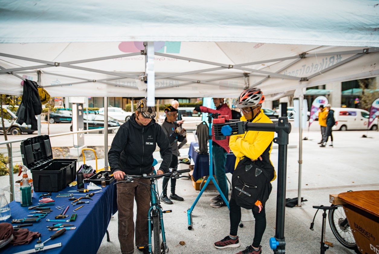 A Cycle City mechanic looks over a Go by Bike Week participant's bike at a Celebration Station.