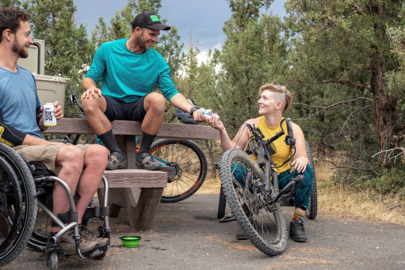 Three friends share beers after mountain biking.