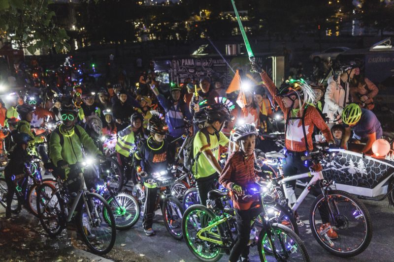 A group of people get ready to ride at Bike the Night. They have their bikes decorated with various lights and glow-in-the-dark decorations.