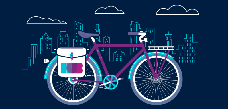 An illustration of a bike with rear panniers. The white panniers have the blue, pink and purple HUB logo on it. The Vancouver city landscape is behind the bike illustration.