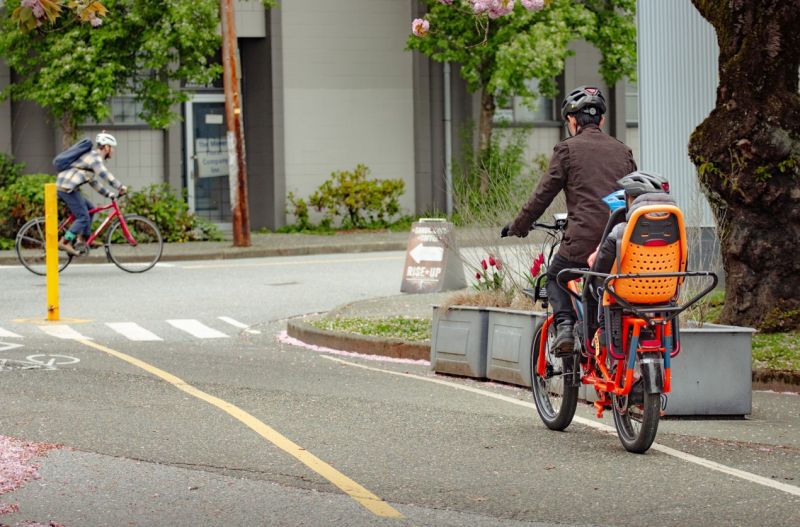 A father and his children cycle in a bike lane in Vancouver. Photo credit: Luke Hubner.